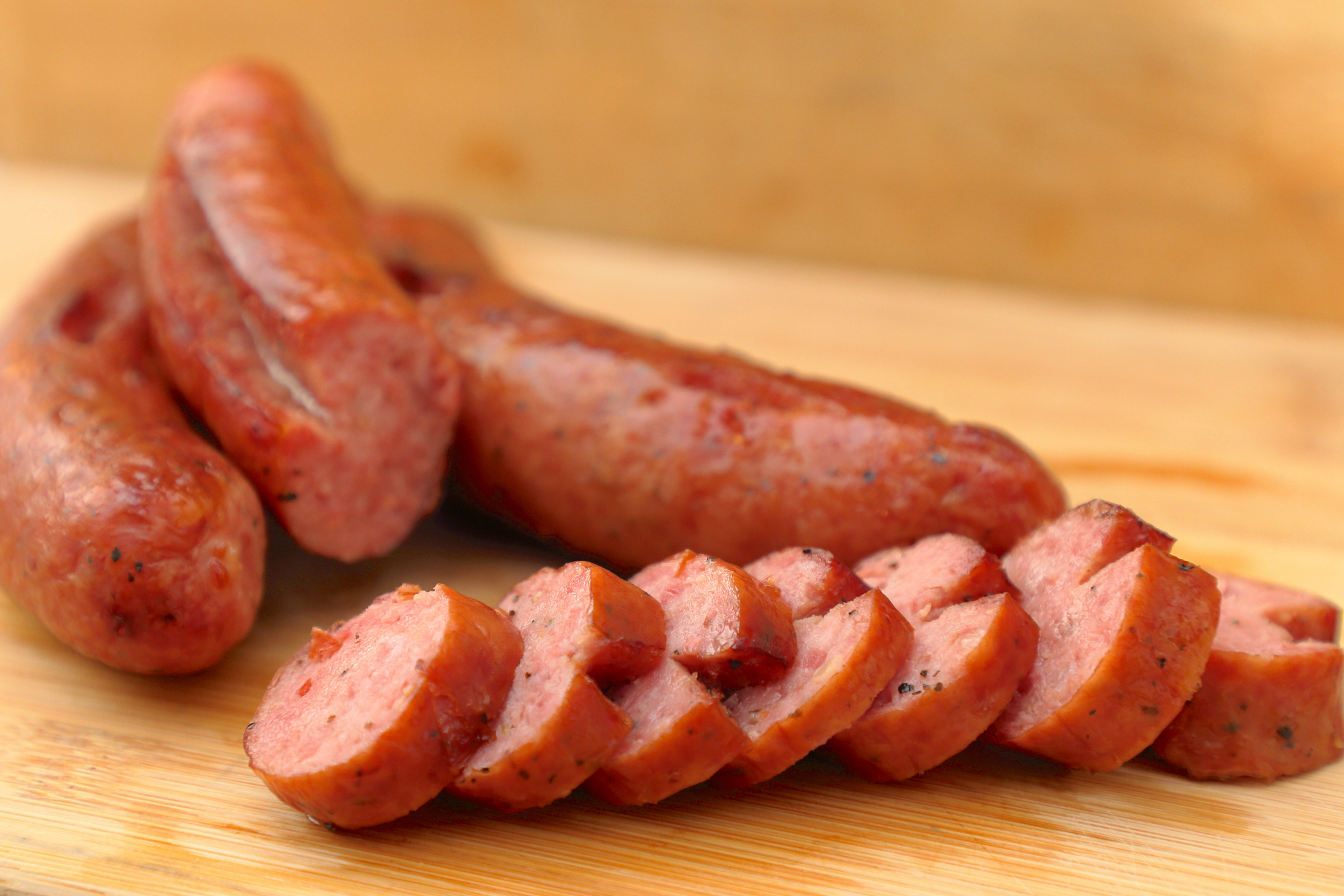 A picture of the smoked sausage sliced on the wooden table. The front row of sausage slices are in-focus.